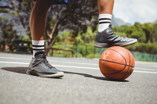 Close up of man standing with one leg on basketball at court
