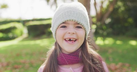 Happy girl with missing tooth in autumn garden smiling brightly