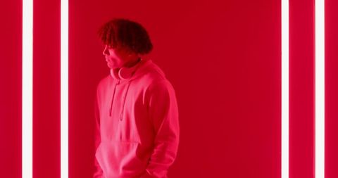 Young man wearing headphones in vibrant neon red light