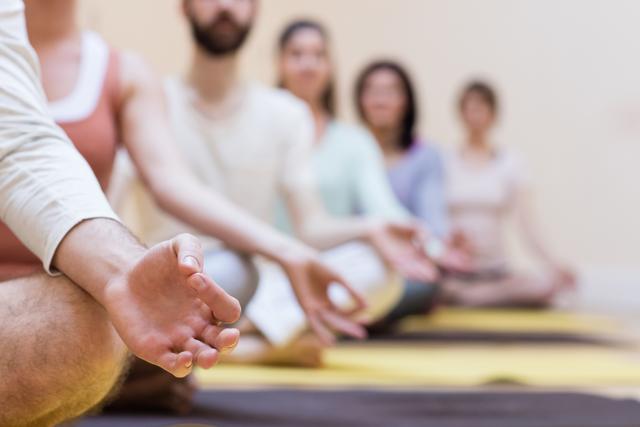 Group of people sitting on exercise mats in a fitness studio, meditating together. Ideal for promoting wellness programs, mindfulness workshops, yoga classes, and mental health awareness campaigns.