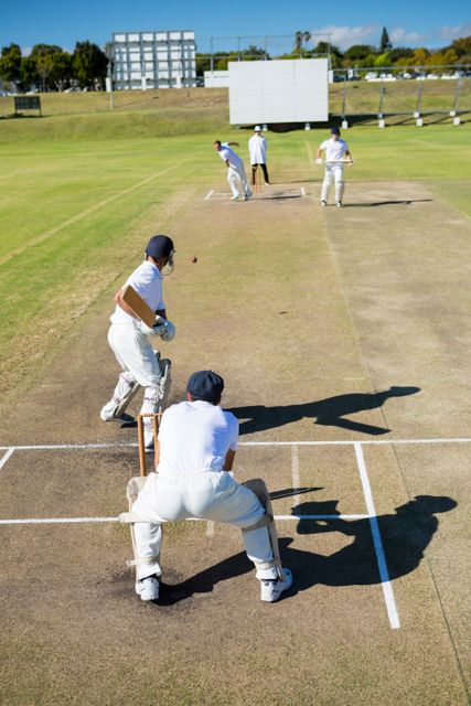 Players actively participating in a cricket match on a bright sunny day. Ideal for use in sports magazines, advertisements for cricket equipment, or websites promoting cricket events.