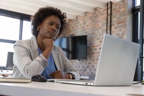 Confident professional woman engages in laptop work at modern office
