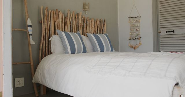 This visual captures a cozy rustic bedroom featuring a unique wooden headboard and pristine white bedding matched with striped pillows. Such a neutral and calming decor is ideal for advertisements related to interior design, home decor inspiration, online furniture catalogs, and lifestyle blogs focused on home living and aesthetics.