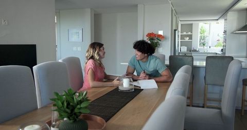 Young couple discussing paperwork at dining table
