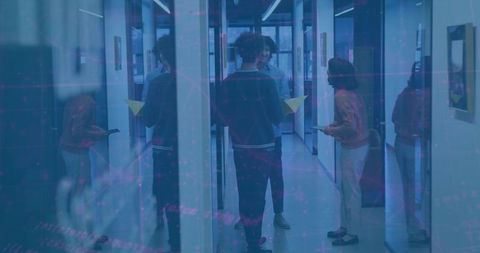 Colleagues collaborating in modern glass corridor holding yellow folder and tablet