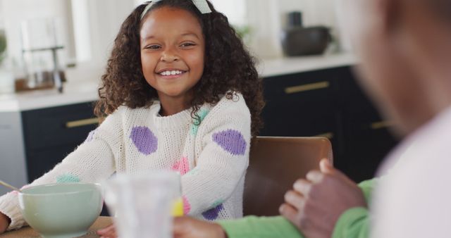 Image of happy african american daughter laughing with parents at dinner table. Family, domestic life and togetherness concept digitally generated image.