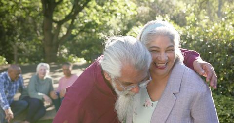 Joyful Senior Couple Embracing Outdoors with Friends in Garden