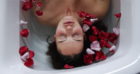 Woman Relaxing in Bath with Floating Rose Petals