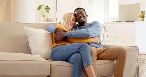 Cheerful Interracial Couple Embracing on Cozy Sofa at Home