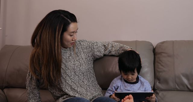 Mother and son using tablet on sofa at home - Download Free Stock Images Pikwizard.com