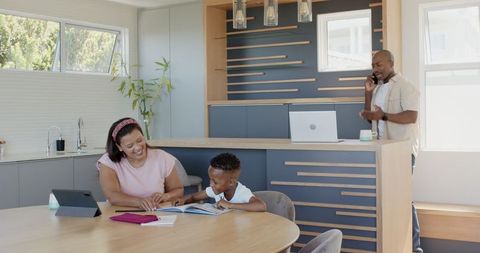 Diverse Family in Kitchen: Mother Helping Son Study, Father on Phone