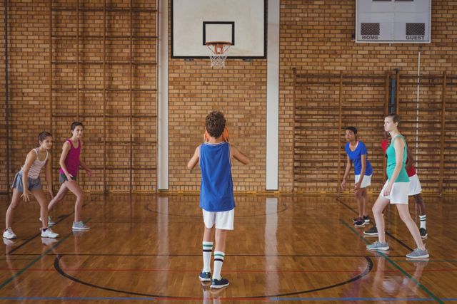 High school boy preparing to take a penalty shot in a basketball game. Teammates and opponents are positioned on the court, ready for action. Ideal for illustrating youth sports, teamwork, school activities, and physical education.