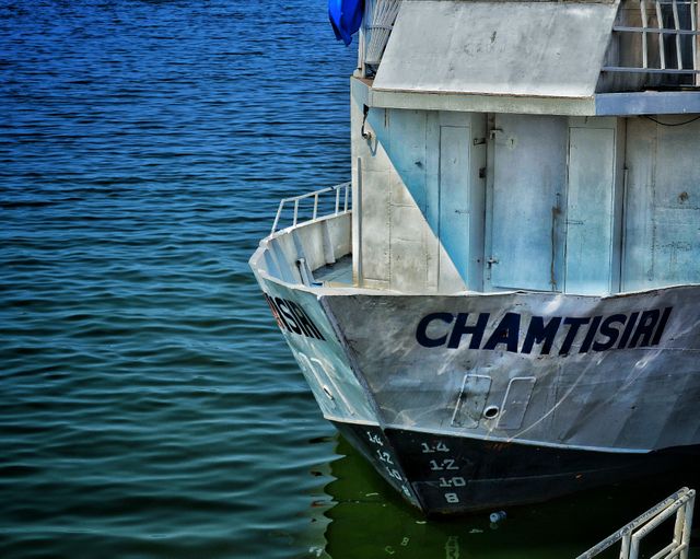 Bow of fishing boat docked in calm blue sea. Ideal for themes of maritime activities, fishing, nautical transportation, and waterfront tranquility.