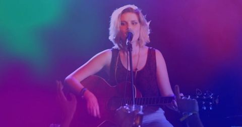 Teen musician performing with acoustic guitar on stage