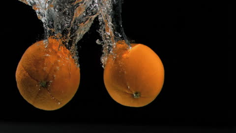 Fresh Oranges Plunging into Splashing Water