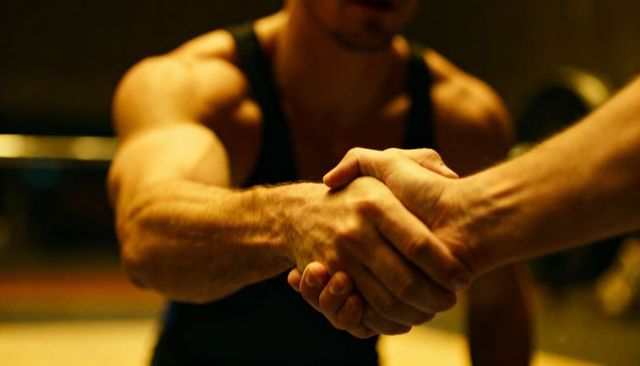 Muscular men shaking hands in gym showing strength, camaraderie and firm grip post-workout