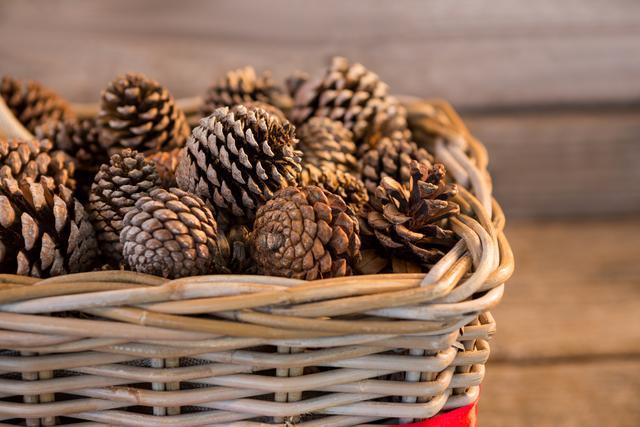 Pine cones in wicker basket on wooden plank during christmas time