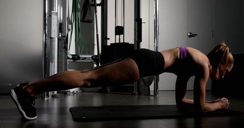 Focused female athlete practicing plank in fitness studio