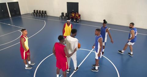 Diverse Basketball Players Training with Coach on Indoor Court