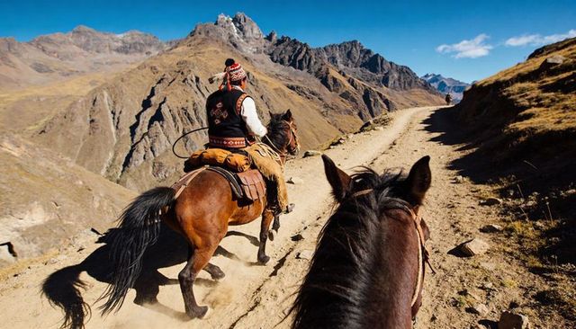 Andean horseback riding on high mountain trail with chullo-clad rider and rugged peaks