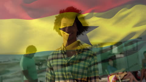 Smiling African American Man with Waving Ghana Flag at Beach