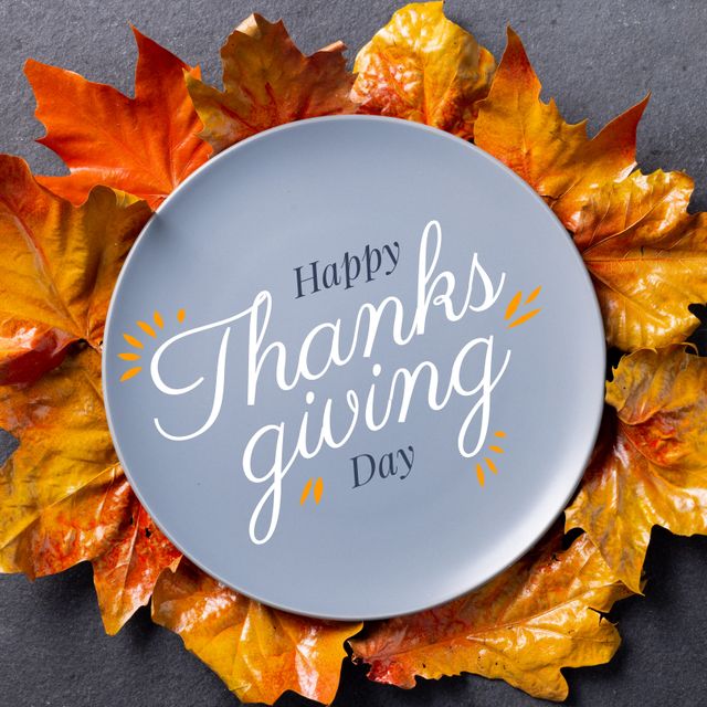 Plate with 'Happy Thanksgiving Day' text on a grey surface surrounded by vibrant colorful autumn leaves. This image is perfect for seasonal holiday promotions, greeting cards, and festive decoration ideas.