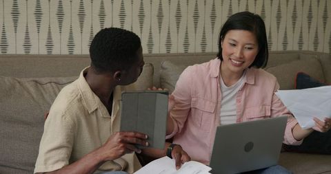 Couple Discussing Plans Together on Sofa with Laptop and Documents
