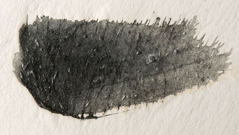 Tapering black ink brushstroke on cold-press paper with granular texture