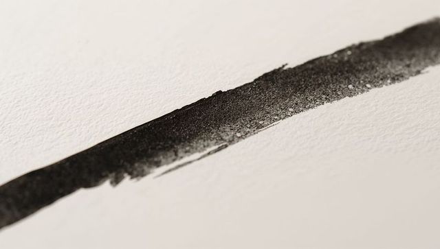 Slanted black ink stroke showing pigment grain and paper texture, minimalist abstract