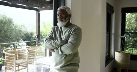 Mature Man Contemplating by Glass Door in Tranquil Home