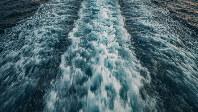Foamy boat wake cutting through deep blue ocean waters with motion blur and reflections