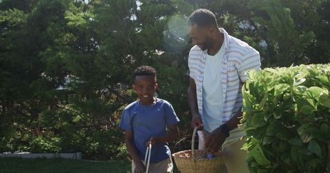 African american father and son bonding during backyard egg hunt on sunny afternoon