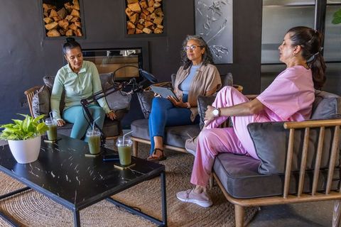 Women recording podcast in cozy lounge with boom microphone, casual chat and collaboration