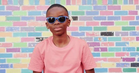 Stylish boy with sunglasses against colorful brick wall