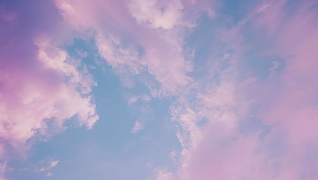 Pastel Pink Clouds Against Serene Blue Sky Background