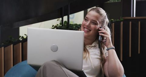 Confident Businesswoman Multitasking with Smartphone and Laptop in Modern Office