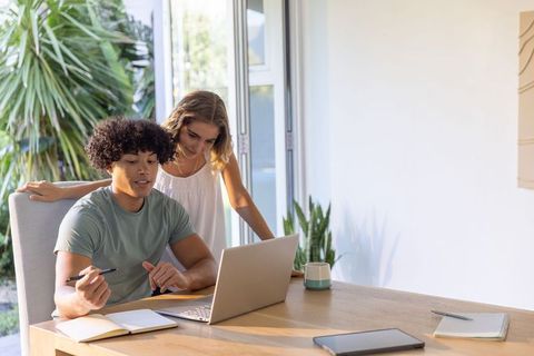 Young couple collaborating on laptop in sunlit home workspace with indoor plants