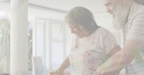 Senior man supporting smiling older woman using walker in bright home caregiving moment