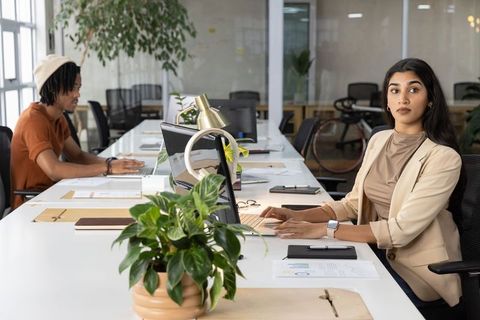 Diverse professionals collaborating in modern open-plan coworking office with greenery