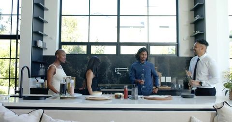 Friends Chatting and Pouring Drinks at Modern Kitchen Island in Bright Open-Plan Home