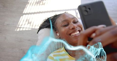 Woman relaxing at home with wireless earbuds using smartphone