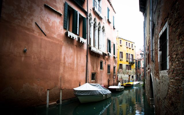 Venice’s charming canals exemplify the city's unique blend of historical architecture and serene waterway views. This image showcases a typical Venetian canal flanked by colorful buildings with boats floating on the calm water. Ideal for travel blogs, tourism websites, and promotional materials highlighting European destinations or boating experiences.