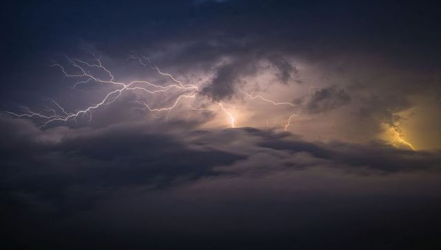 Cumulonimbus lightning across night sky with branching bolts and orange glow, epic storm