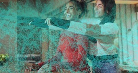 Mother helping teen daughter try on sweater in cozy living room with turquoise overlay