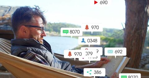 Man Relaxing on Hammock Receiving Digital Notifications in Nature