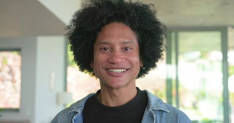 Smiling african american man wearing denim jacket, nose hoop piercing, minimalist home