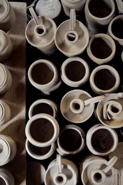 Overhead view of an assortment of clay jugs placed closely together at different stages of formation. Ideal for illustrating concepts related to pottery, craftsmanship, traditional arts, and the creative process. Suitable for use in blogs, articles, and educational content about pottery making, artisan skills, and ceramic art.