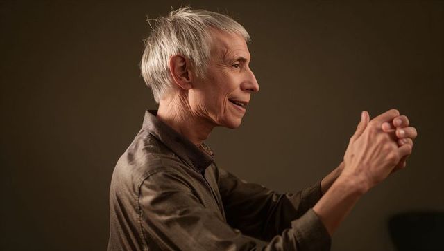 Senior man holding hands and looking right in warm intimate studio portrait