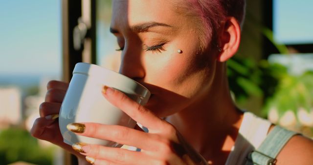 Close-up of Woman Sipping Coffee in Sunlight with Pink Hair and Piercing - Download Free Stock Images Pikwizard.com