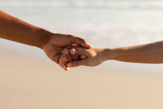 Close-up of couple holding hands of each other on the beach